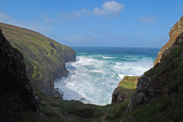 A coastal cliff with a rugged coastline, a clear sky, and the ocean.