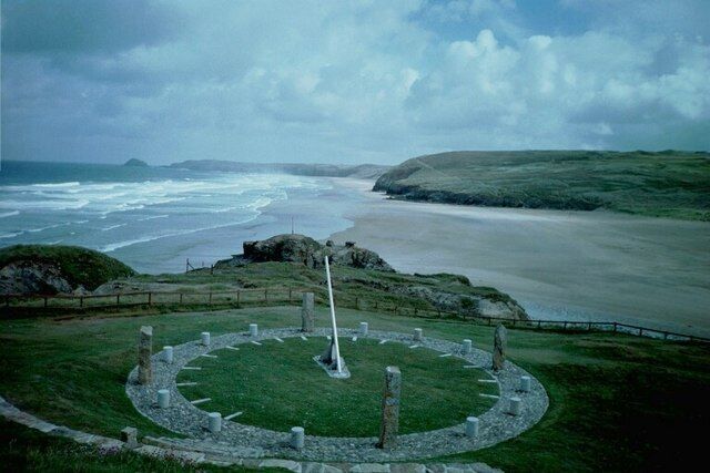A coastal landscape with a circular stone structure and a white obelisk in the center.