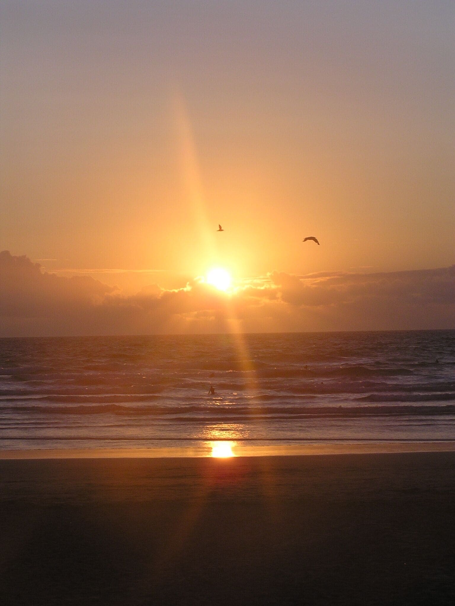 Un atardecer sobre el océano, con el sol reflejándose en el agua.