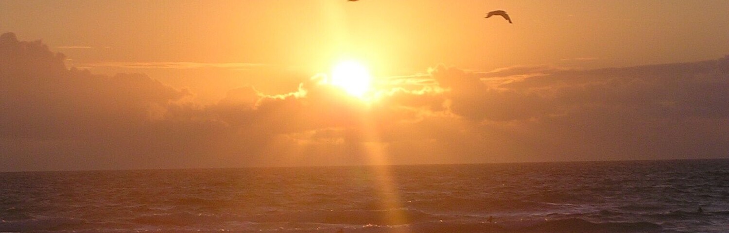Un atardecer sobre el océano, con el sol reflejándose en el agua.