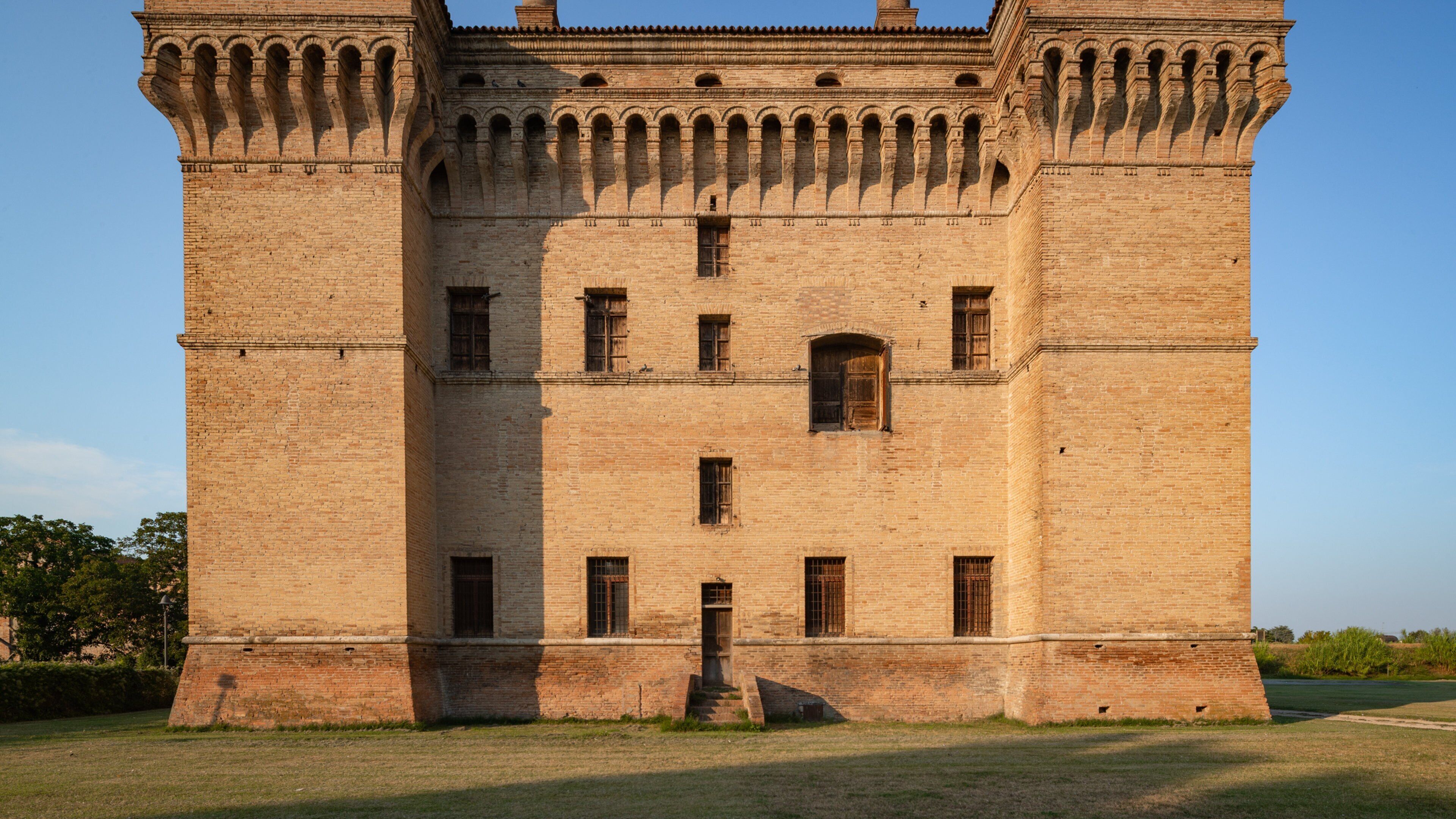 A large, historic brick castle with multiple arched windows and a central entrance.