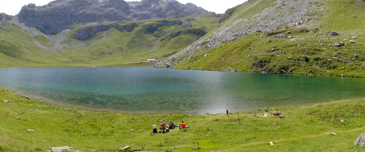 A lake surrounded by green hills and rocky mountains.