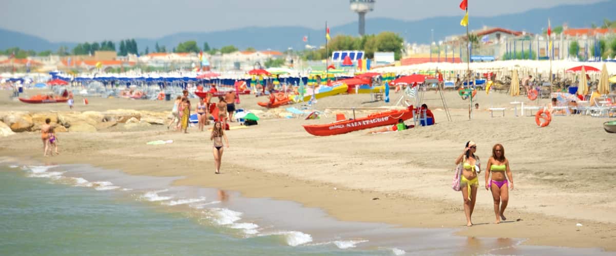 Une plage bondée, avec des gens, des parasols et des bateaux.