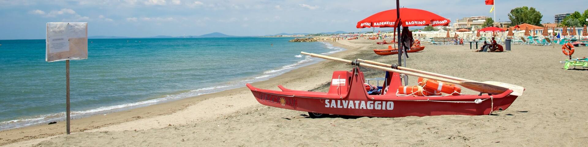 A beach with a lifeguard boat, umbrellas, and a clear blue sky.