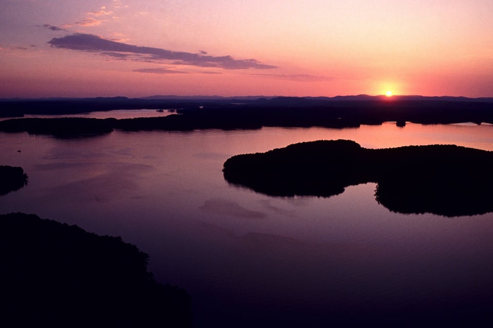 A sunset over a calm lake with several islands.