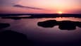 A sunset over a calm lake with several islands.