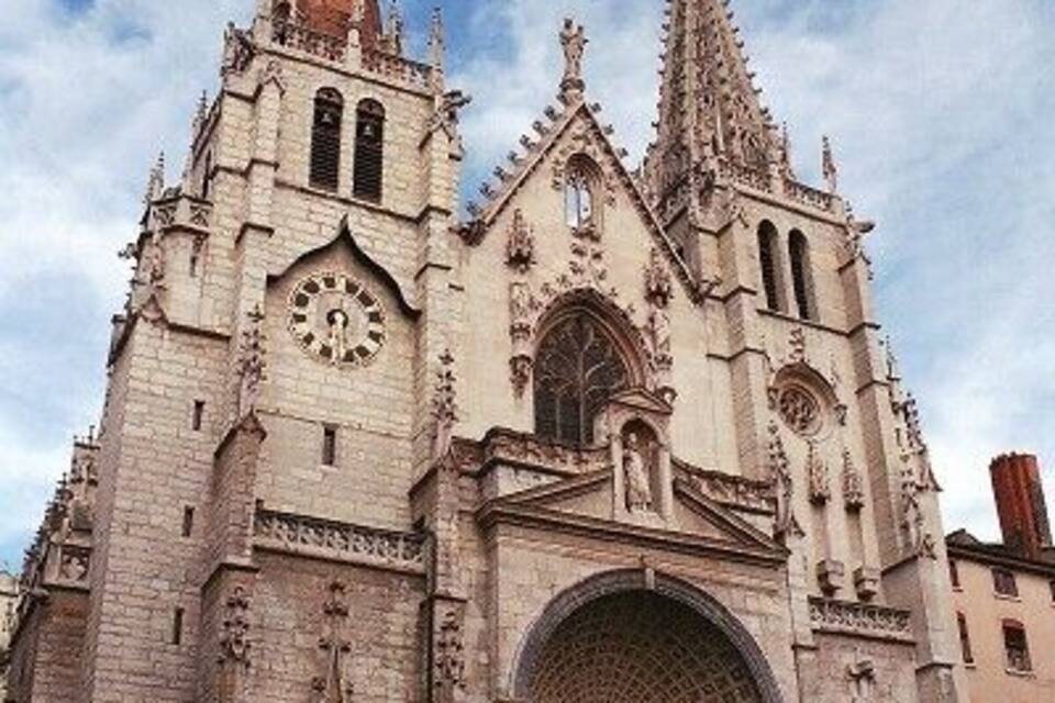A Gothic cathedral with two spires, a large arched entrance, and a clock tower.