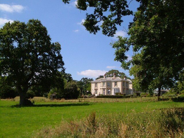A large house surrounded by lush green fields and trees.