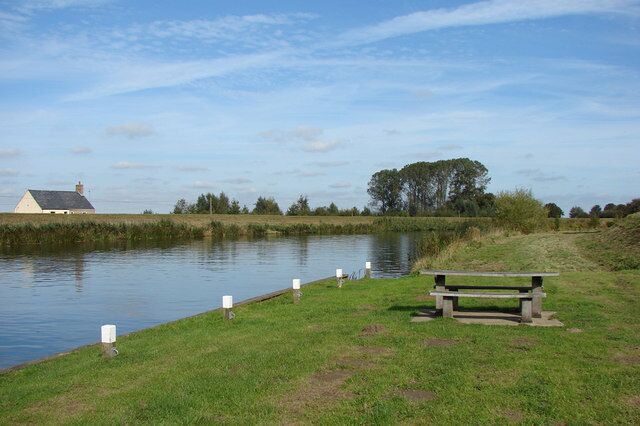 A grassy area with a bench and a body of water.