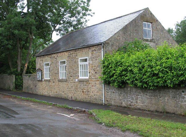A stone building with a sloped roof and a small window.