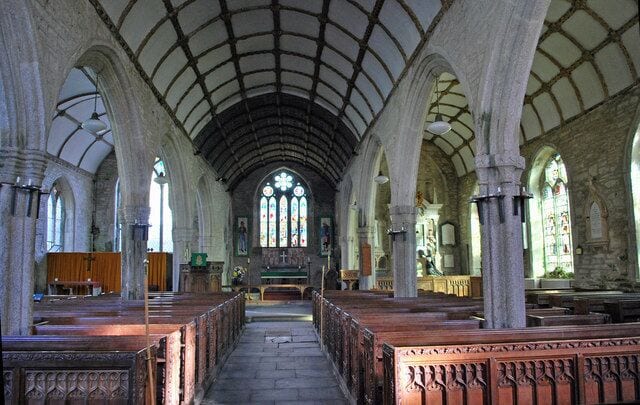 An interior of a church with arched ceilings, pews, and stained glass windows.