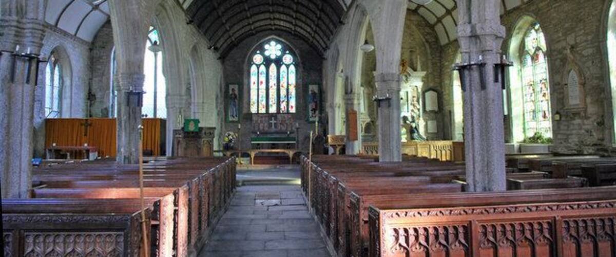 An interior of a church with arched ceilings, pews, and stained glass windows.