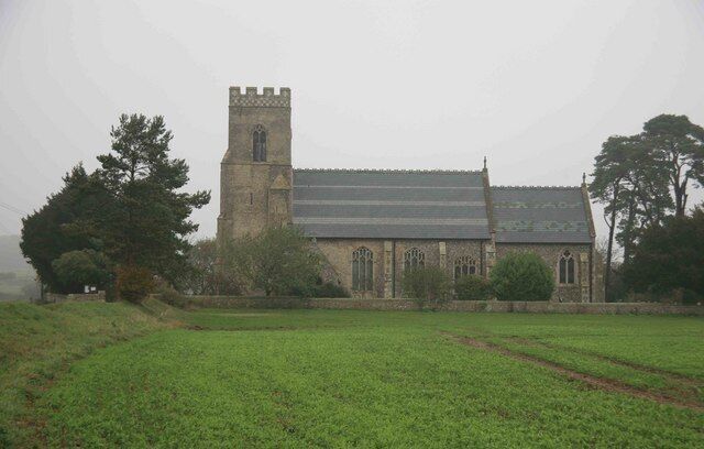 A church with a tall tower and a large field in the foreground.