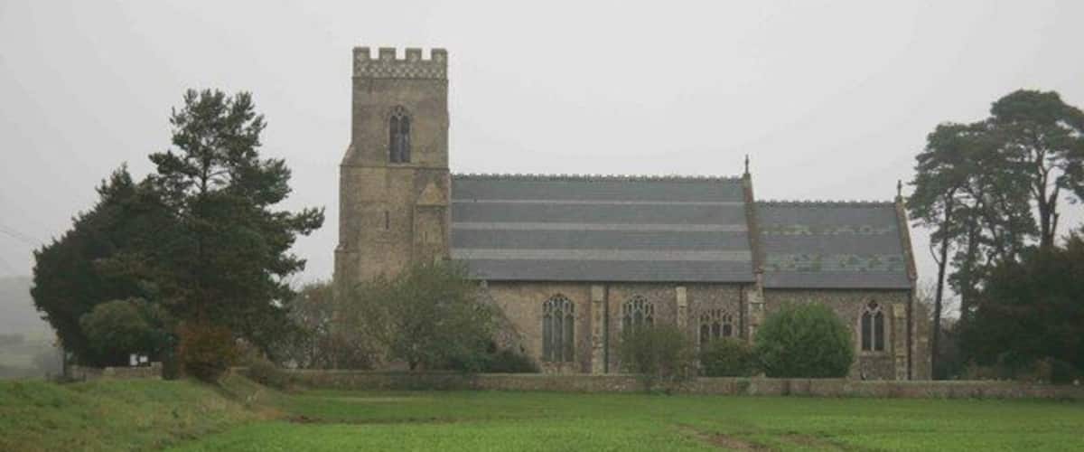 A church with a tall tower and a large field in the foreground.