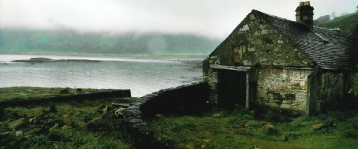 A stone house by a misty coastal area.