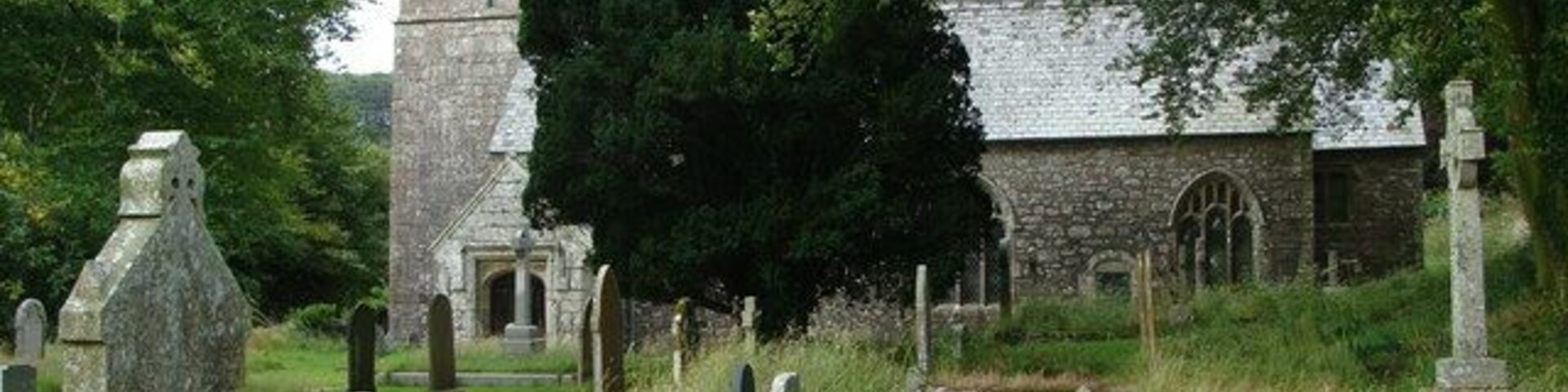 Un cementerio con cruces de piedra y una alta torre.