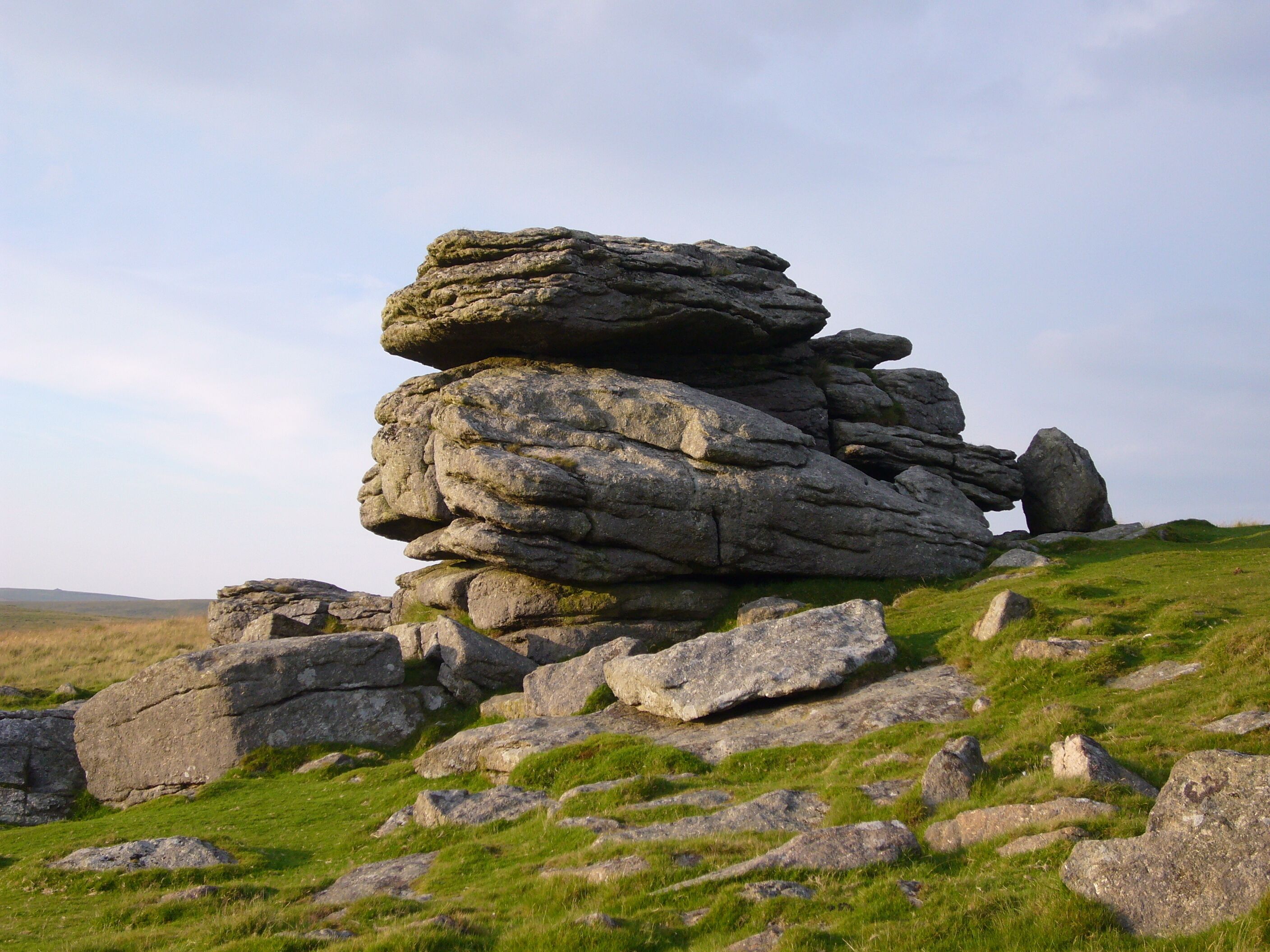 A stack of large rocks in a grassy field.