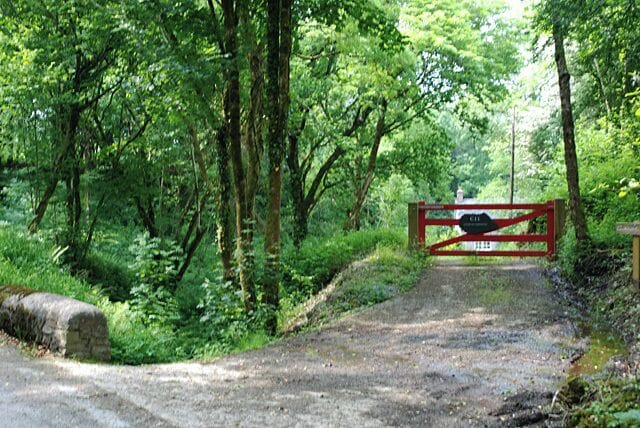 A forested area with a red gate and a sign that reads "Private Road."
