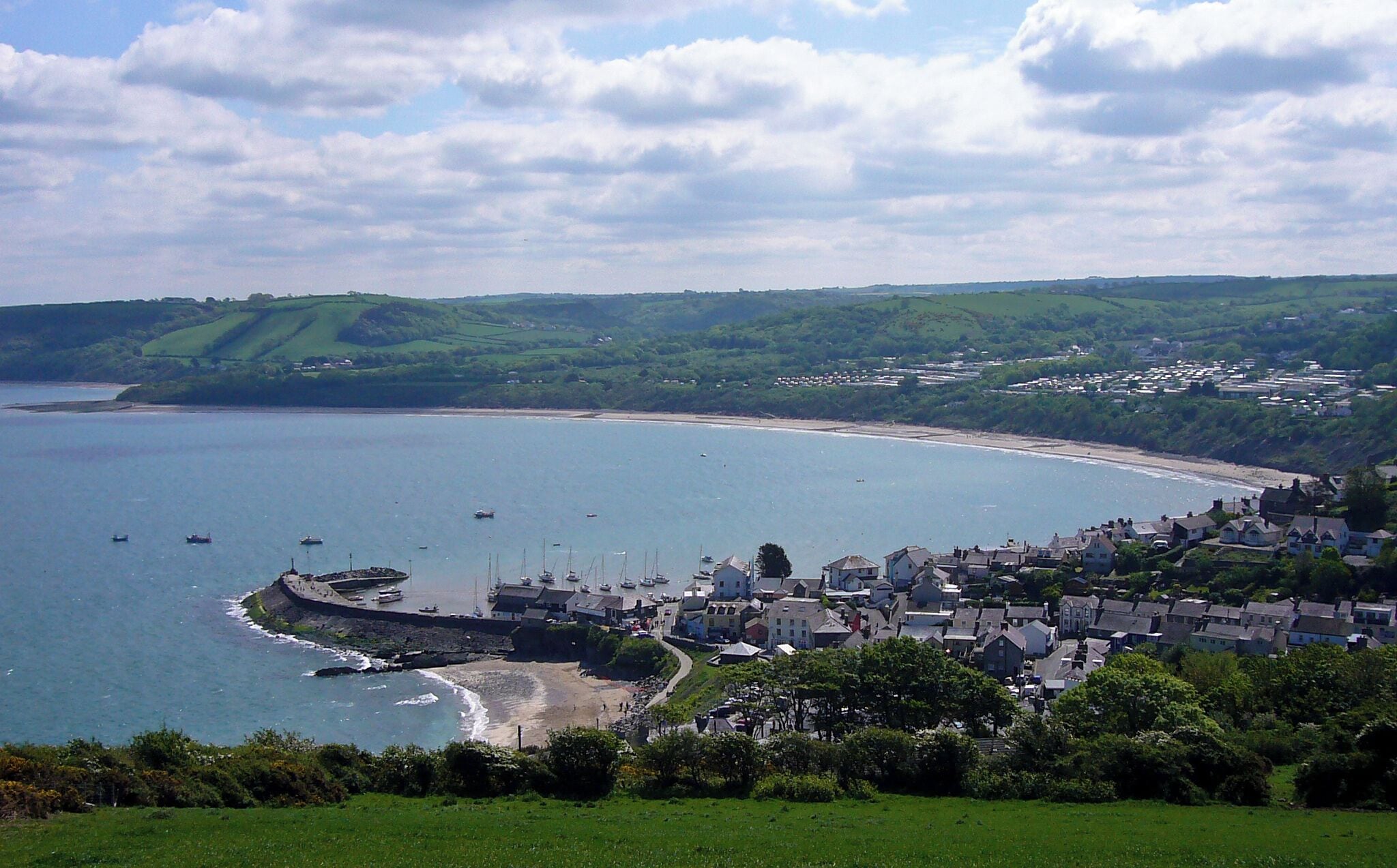 A coastal town with a beach, boats, and houses.