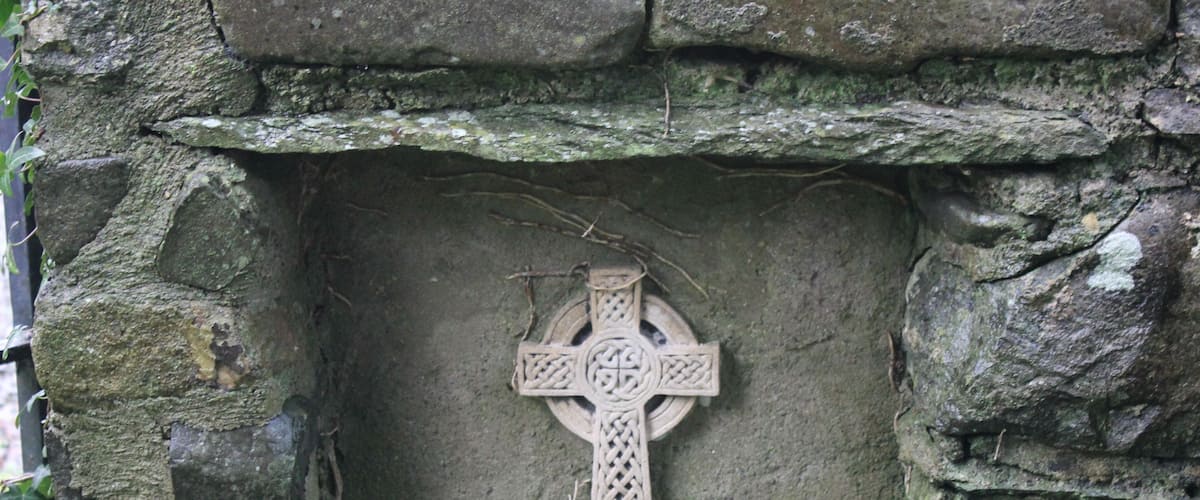 A stone wall with a carved cross and a small candle.