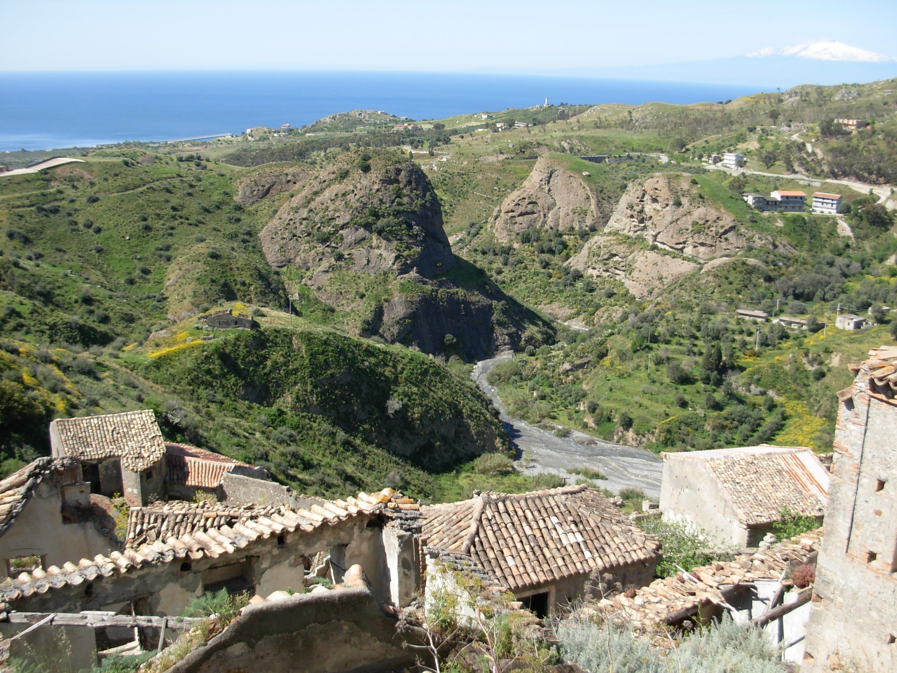 A mountainous landscape with terraced fields, traditional buildings with tiled roofs, and a winding road.