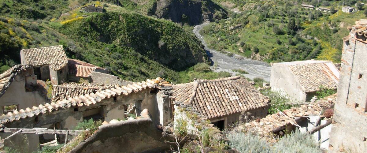 A mountainous landscape with terraced fields, traditional buildings with tiled roofs, and a winding road.