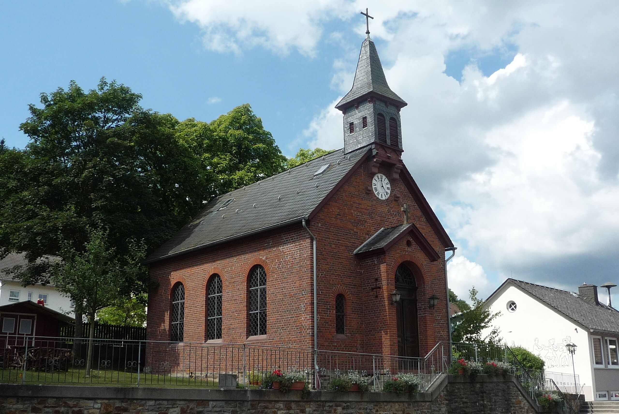 A brick church with a steeple and a clock.