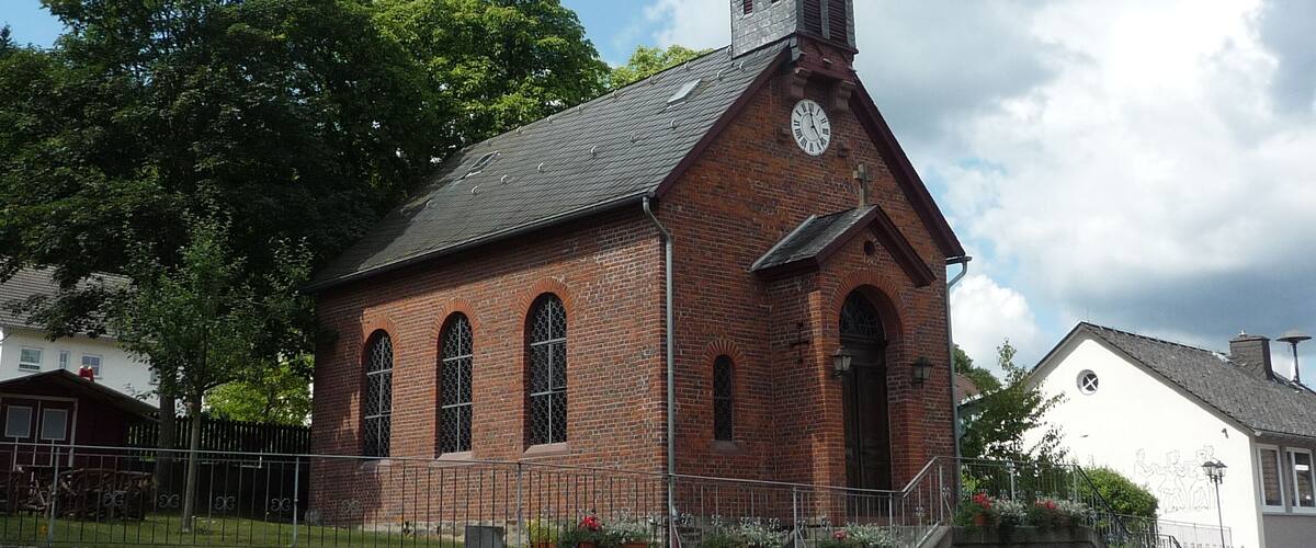 A brick church with a steeple and a clock.