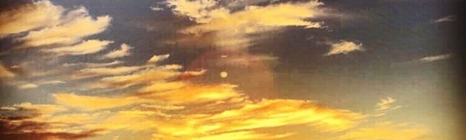 A sunset over a beach with clouds in the sky.