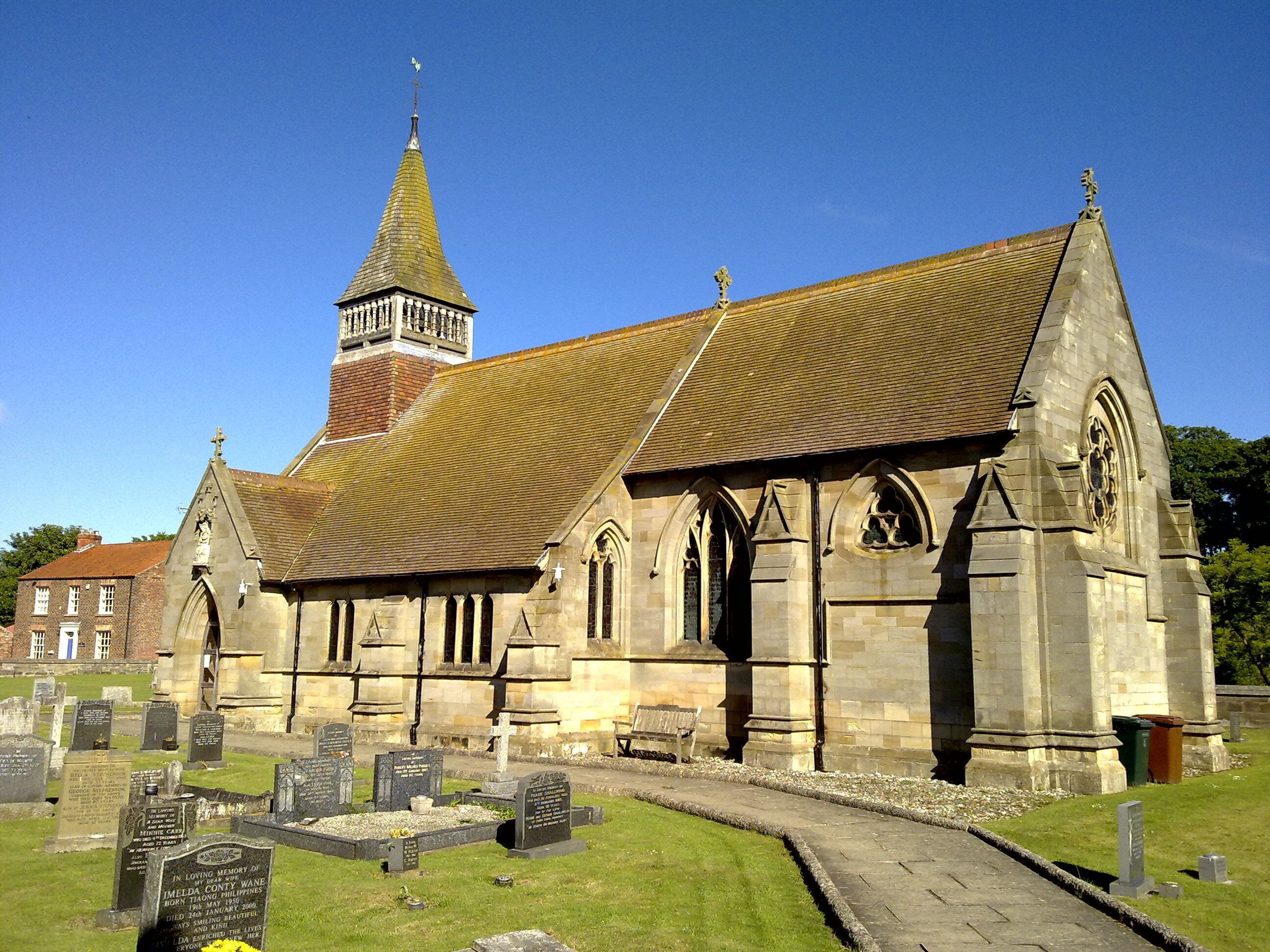 A church with a tall steeple and a graveyard in front.