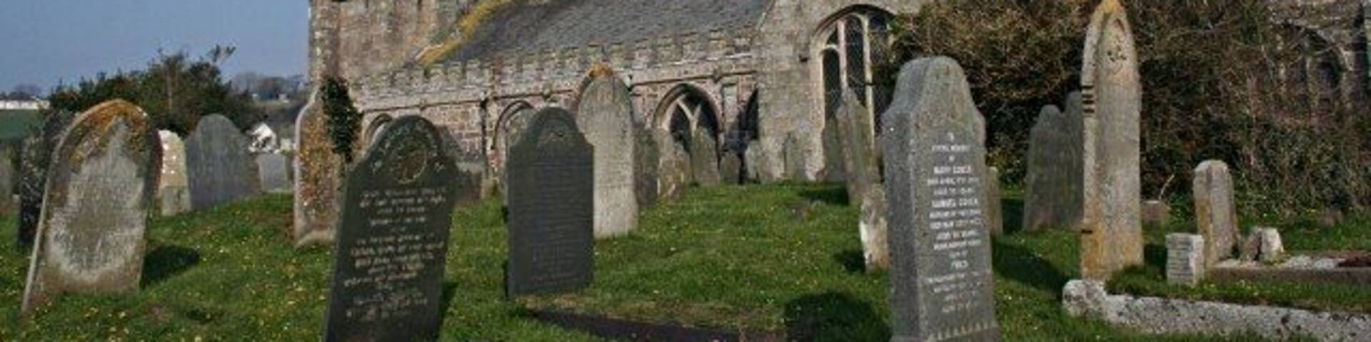 Una iglesia con una torre alta y un cementerio con lápidas.