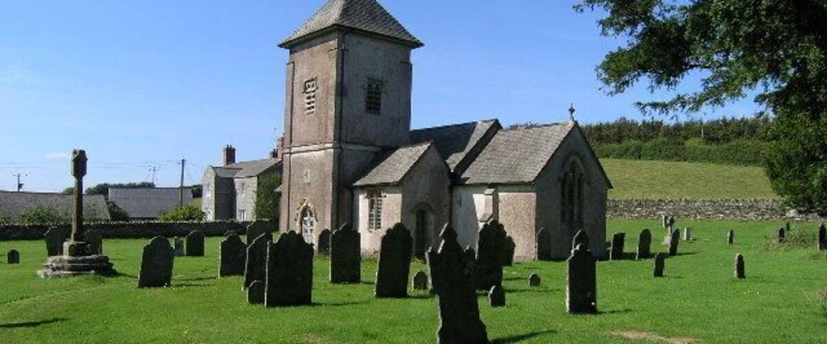 A church with a bell tower and a cemetery with numerous gravestones.