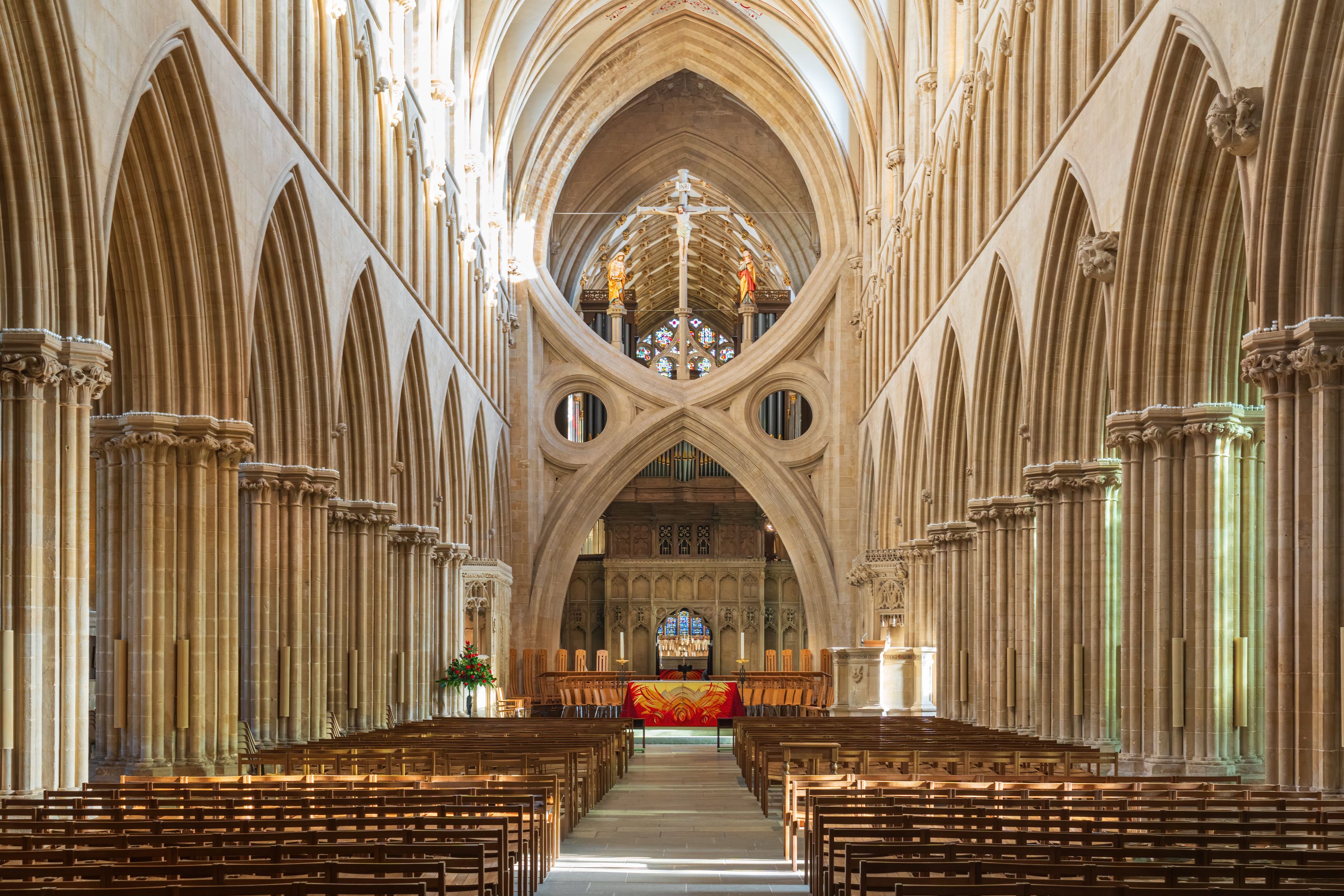 A cathedral interior with high vaulted ceilings, arched windows, and a central altar.