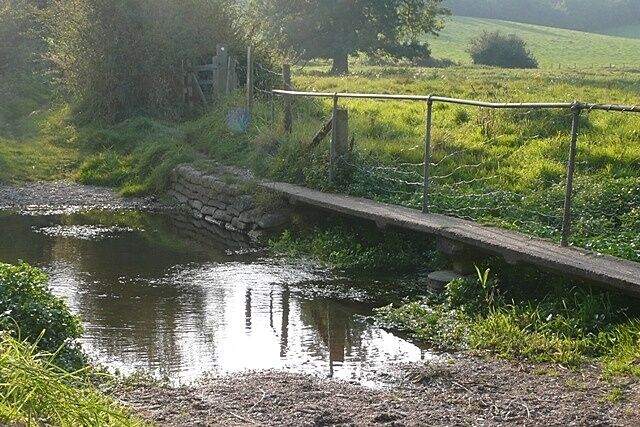 A narrow waterway with a stone bridge and a metal railing.