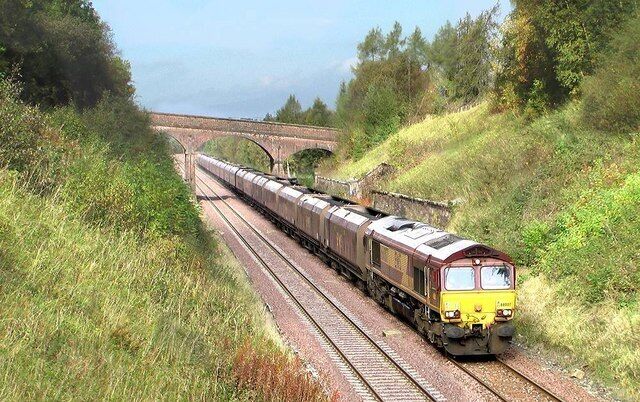 Site of Crosby Garrett station This south bound coal train is passing the site of Crosby Garrett station. Closed in 1956, the platforms were set into the cutting needing hefty retaining walls. The station house which still exists as a private dwelling is hidden from view behind the trees on the right of the overbridge.