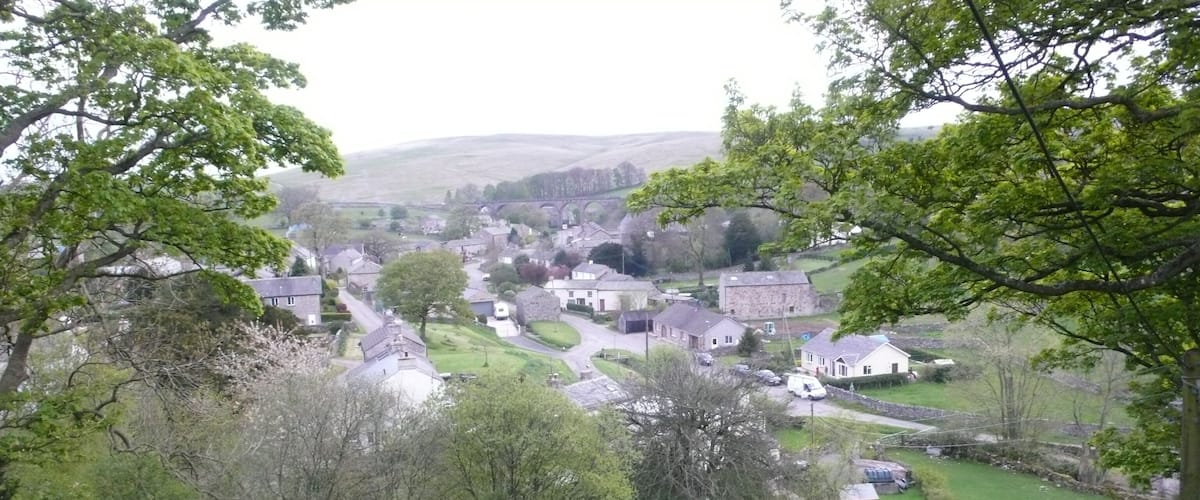 A rural village with houses, a stone bridge, and green fields.