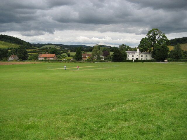 Bradenham: The Green Lowering skies threaten a cricket match on The Green. The White House is obvious on the right.