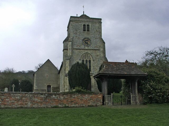 A church with a clock tower, a brick wall, and a small pavilion.