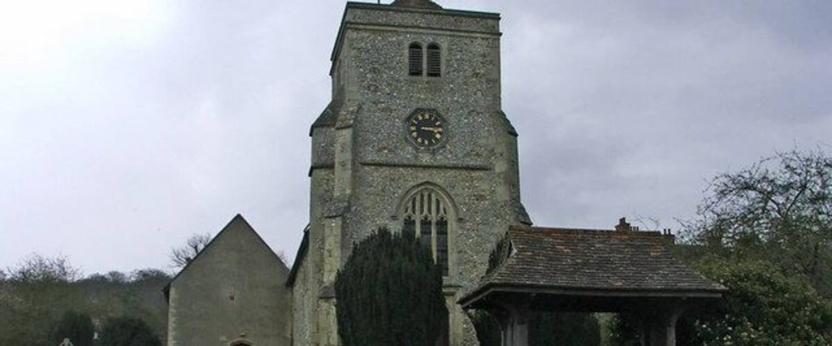 A church with a clock tower, a brick wall, and a small pavilion.