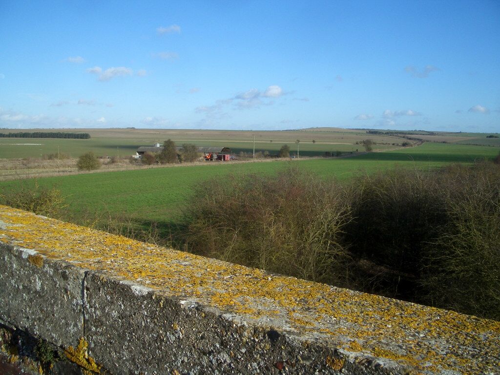 View from a Bridge Looking from the parapet of an old railway bridge over the open farmland on Blewbury Down. Just to the south of the steep scarp where the chalk downs give way to the flat Thames valley, this area is surprisingly level compared with the usual undulating downland topography. The buildings middle distance were once an extensive pig unit, but were being demolished as this photo was taken.