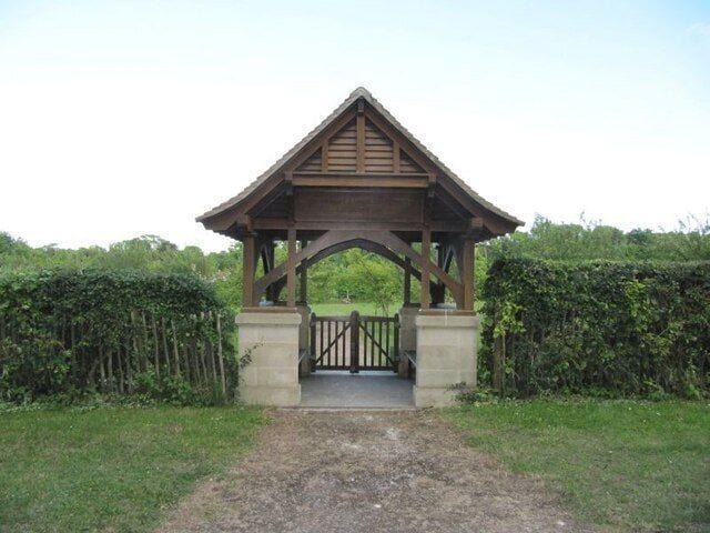 A wooden gazebo with a triangular roof and a gate in the center.