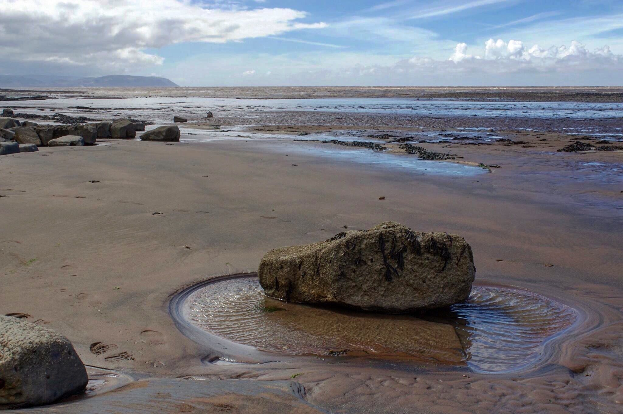 A beach with large rocks and a calm sea.
