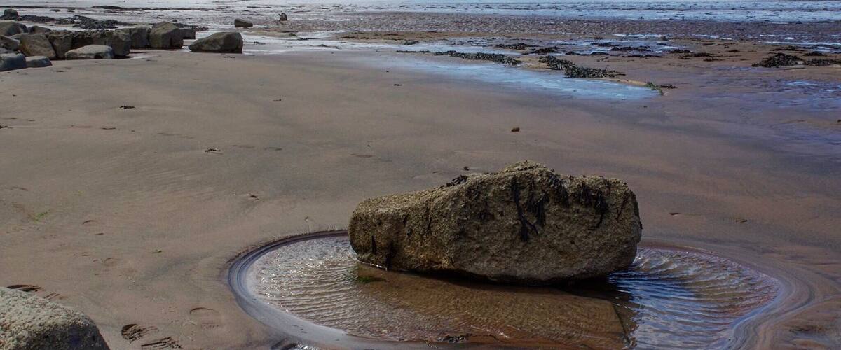 A beach with large rocks and a calm sea.