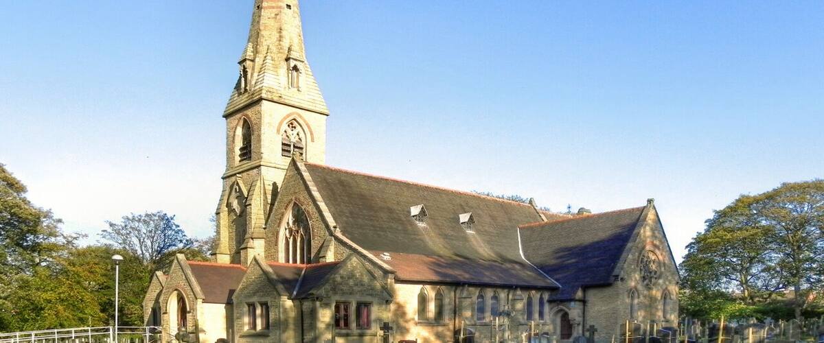 A church with a tall steeple and a graveyard in front.