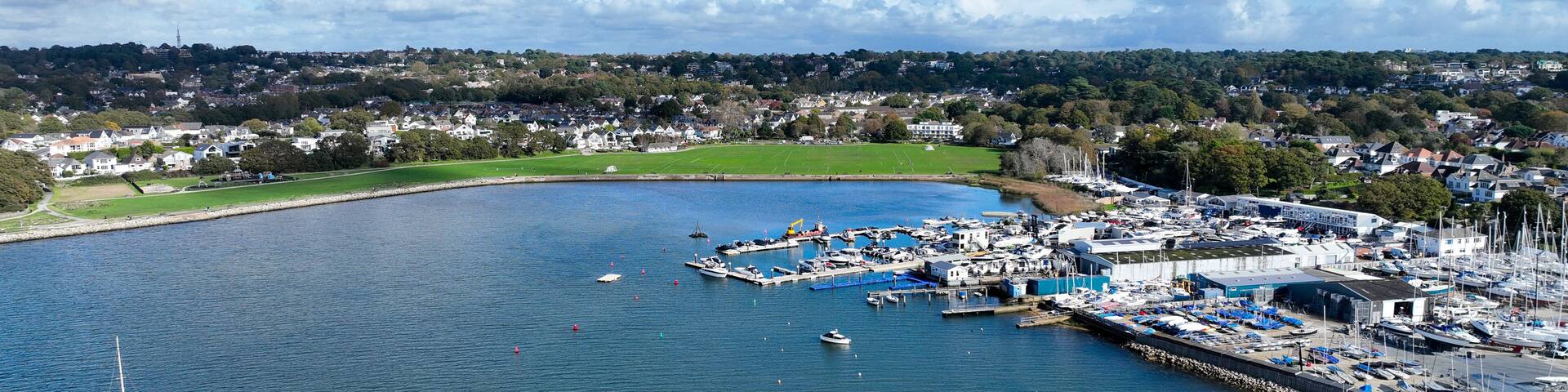 A coastal marina with boats, a pier, and a town in the background.