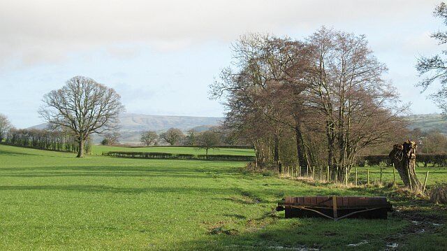 Farmland, Burley A view towards Brown Clee. In the foreground is a roller, a pollarded willow beside a watercourse and further back a line of mature oak trees shows the course of a removed hedge.