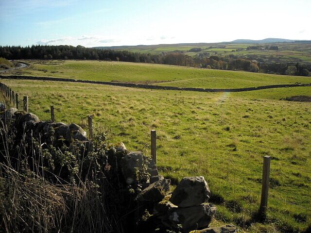 A stone wall, grassy fields, and rolling hills in the distance.