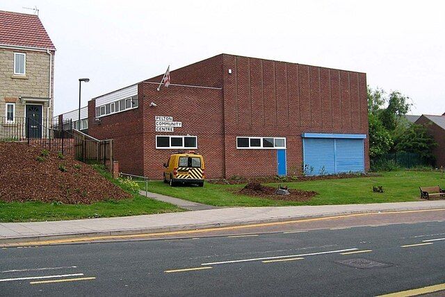 A brick building with a blue garage door, a yellow vehicle, and a pile of dirt in front.
