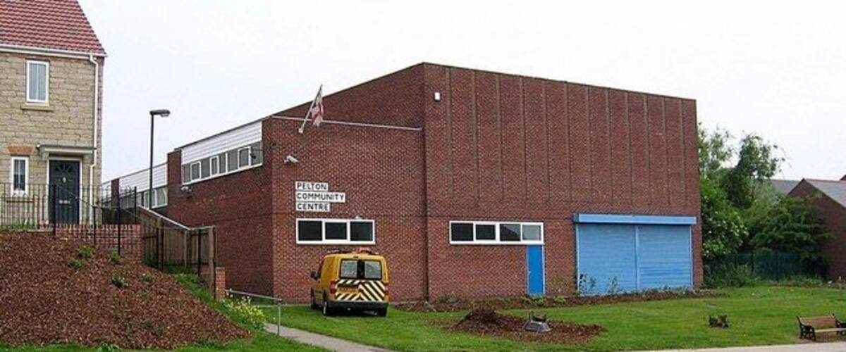 A brick building with a blue garage door, a yellow vehicle, and a pile of dirt in front.