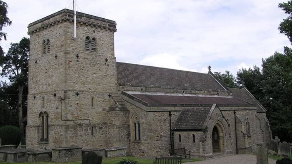 A stone church with a bell tower and a graveyard.
